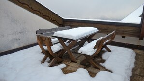 A wooden table and chairs covered in snow, set on a balcony with a view of snow-covered mountains. - HCR 141 - COMFORTABLE apartment 8 pers (Veysonnaz)