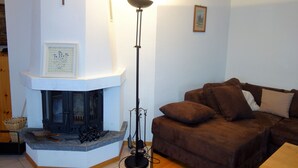 A living room with a fireplace, a brown sofa, and a tall floor lamp. - HCR 141 - COMFORTABLE apartment 8 pers (Veysonnaz)