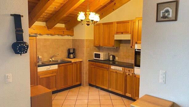 A compact kitchen with wooden cabinets, a microwave, a coffee maker, and a clock on the wall. - HCR 141 - COMFORTABLE apartment 8 pers (Veysonnaz)