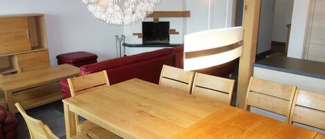 A dining area with wooden furniture, a red sofa, and a unique chandelier.