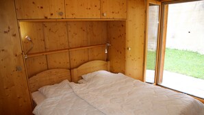 Une pièce en bois avec un lit, une fenêtre et une porte.