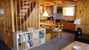 A wooden interior with a staircase, kitchen, dining area, and a bookshelf. - Fontannets 006 QUIET & SUPERIOR chalet 10 pers (Salins)