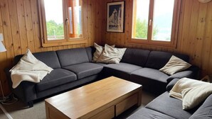 A cozy living room with a sectional sofa, a wooden coffee table, and large windows with a poster on the wall. - Fontannets 006 QUIET & SUPERIOR chalet 10 pers (Salins)
