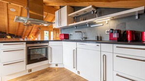 A modern kitchen with white cabinets, stainless steel appliances, and wooden beams.