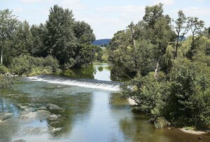 A river with a dam, surrounded by dense trees and a distant mountain. - Cobbler’s Cottage Pembridge, Nr Leominster , Herefordshire (Leominster)