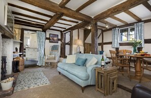 Ground floor: Sitting room with exposed beams, wood burning stove and raised dining area