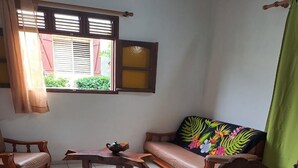 A living room with a sofa, two wooden chairs, a coffee table, and a window with shutters. - Country house in Guadeloupe (Capesterre Belle Eau)