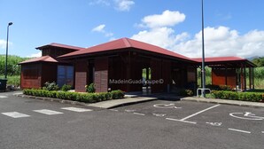 A red-roofed building with a covered entrance and a wheelchair-accessible parking space. - Country house in Guadeloupe (Capesterre Belle Eau)