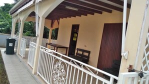 A covered outdoor area with a white railing, a bench, and a table. - Country house in Guadeloupe (Capesterre Belle Eau)