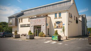 A country shop with a stone facade, a signboard, and a parking area.
