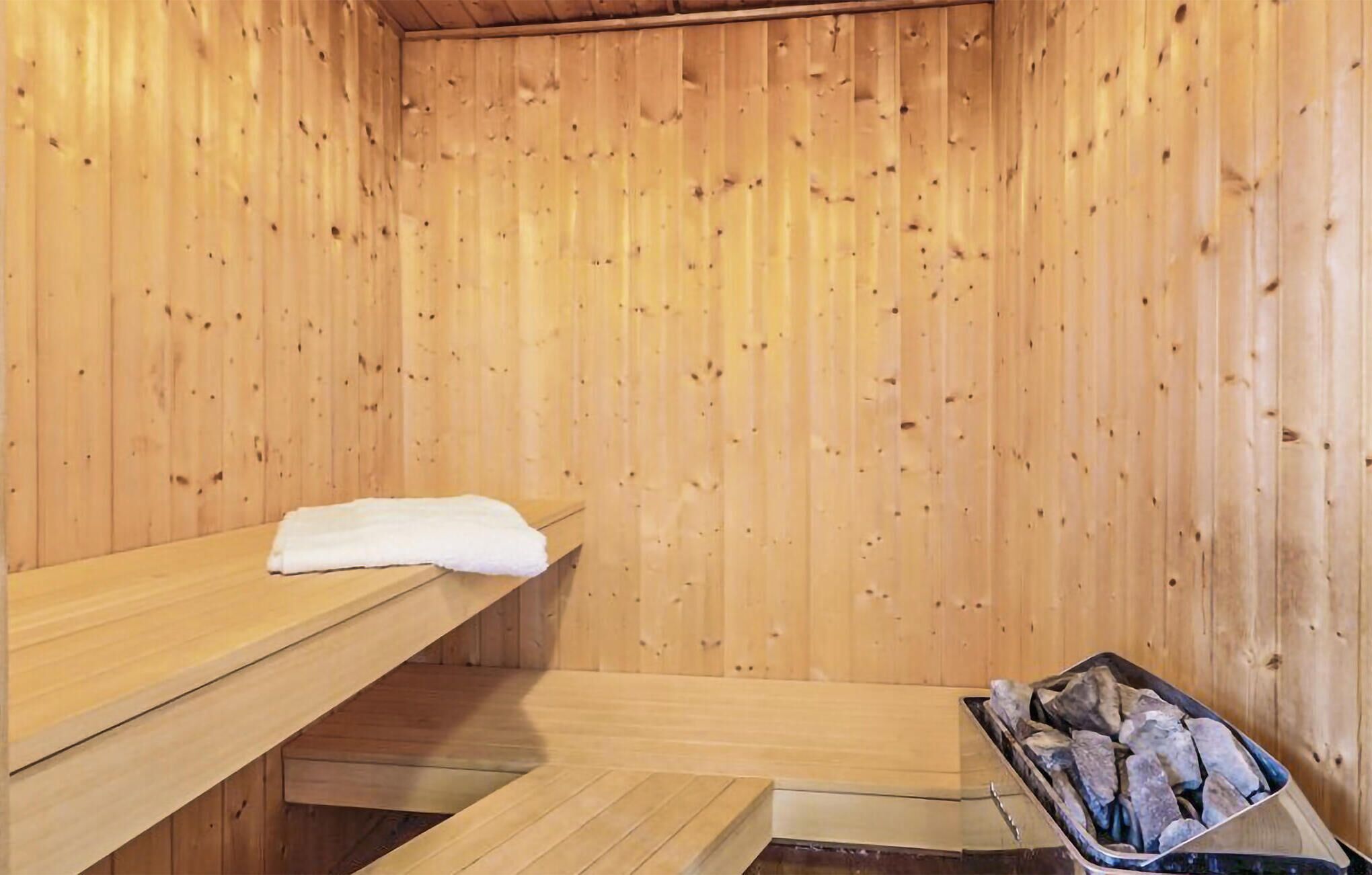A wooden sauna with benches and a tray of stones.