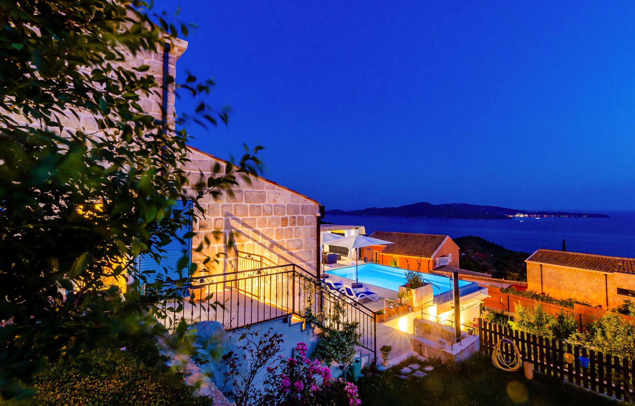 A coastal property with a swimming pool, stone walls, and a view of the sea.