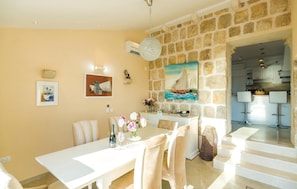 A dining area with a stone wall, a table with chairs, and a painting of a sailboat. - Cozy home in Brsecine (Brsecine)