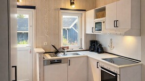 A compact kitchen with white cabinets, a built-in microwave, a coffee maker, and a dishwasher. - Frische Brise 12 - Dorf 3 (Travemünde-Priwall)