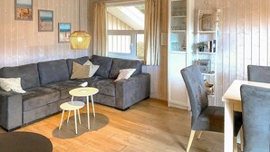 A cozy living room with a grey sectional sofa, a small round table, and a grey armchair. - Frische Brise 12 - Dorf 3 (Travemünde-Priwall)