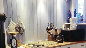 Una cucina con mobili in legno, un piano cottura, una bilancia e diversi utensili da cucina.
