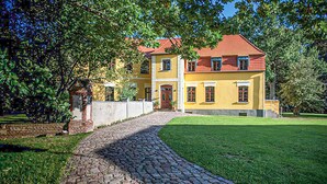 A yellow building with a red roof, a cobblestone path leading to the entrance, and a well-maintained lawn. - Lovely home in Wolin with WiFi (Wolin)