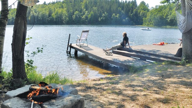 Une jetée en bois s’étendant dans un lac, avec une personne assise sur la jetée.