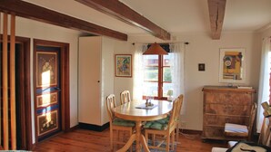 Une salle à manger avec une table et des chaises en bois, une fenêtre avec des rideaux et un buffet en bois.
