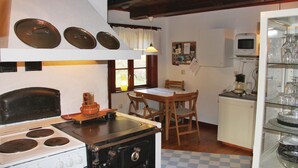 Une cuisine équipée d’une cuisinière, d’une table en bois, de chaises, d’un réfrigérateur et d’un four à micro-ondes.