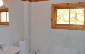 A bathroom with a white sink, a toilet, and a window with a view of trees.
