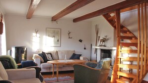 Un salon chaleureux avec une cheminée, des poutres en bois et un escalier.