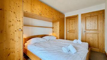 A wooden room with a bed, a door, and a light fixture.