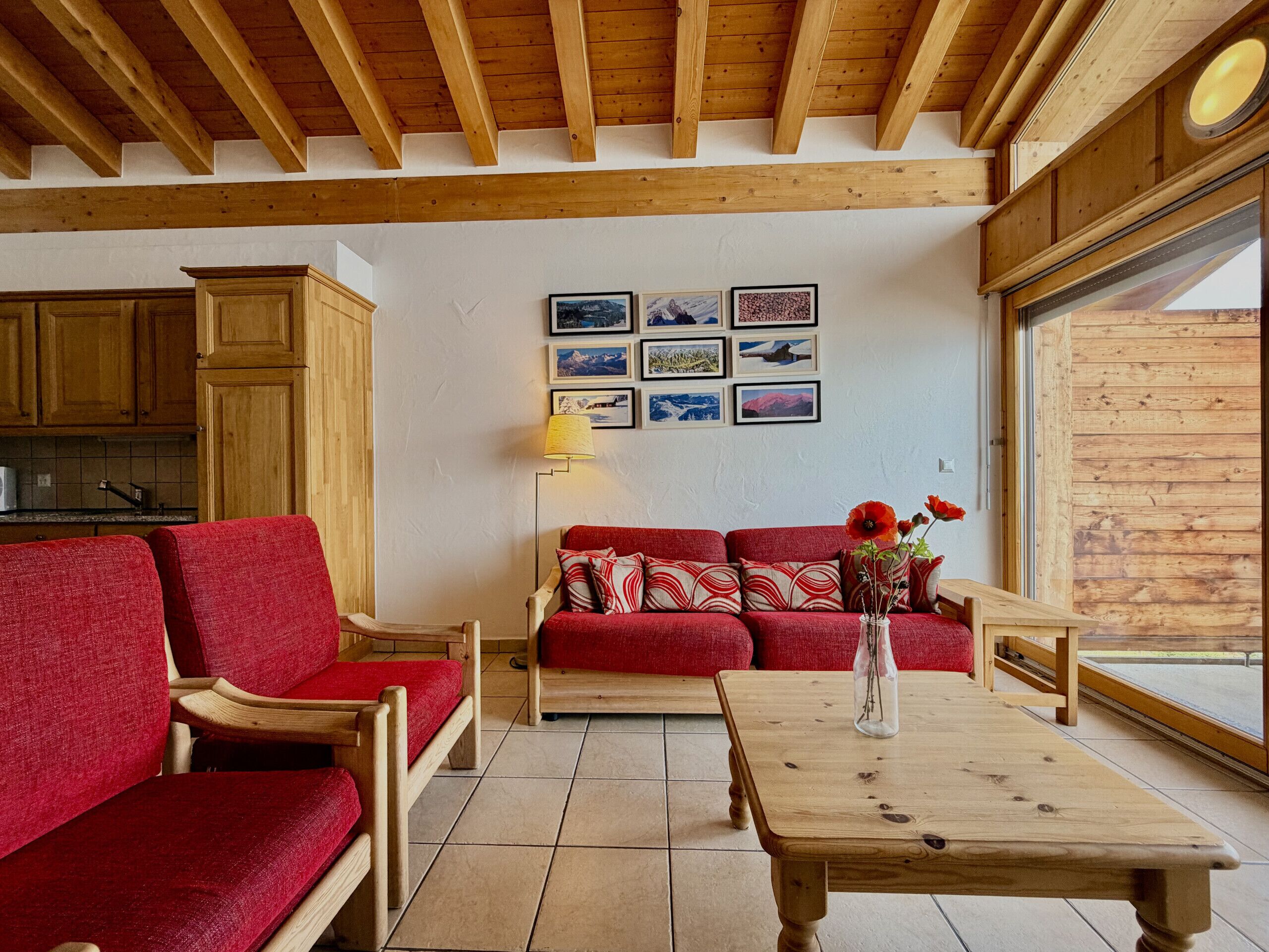 A cozy living room with a red sofa, wooden coffee table, and a wall adorned with framed pictures.