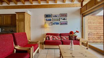 A cozy living room with a red sofa, wooden coffee table, and a wall adorned with framed pictures.