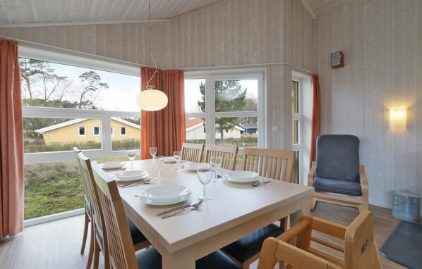 A dining area with a table set for four, large windows, and a view of the outside.
