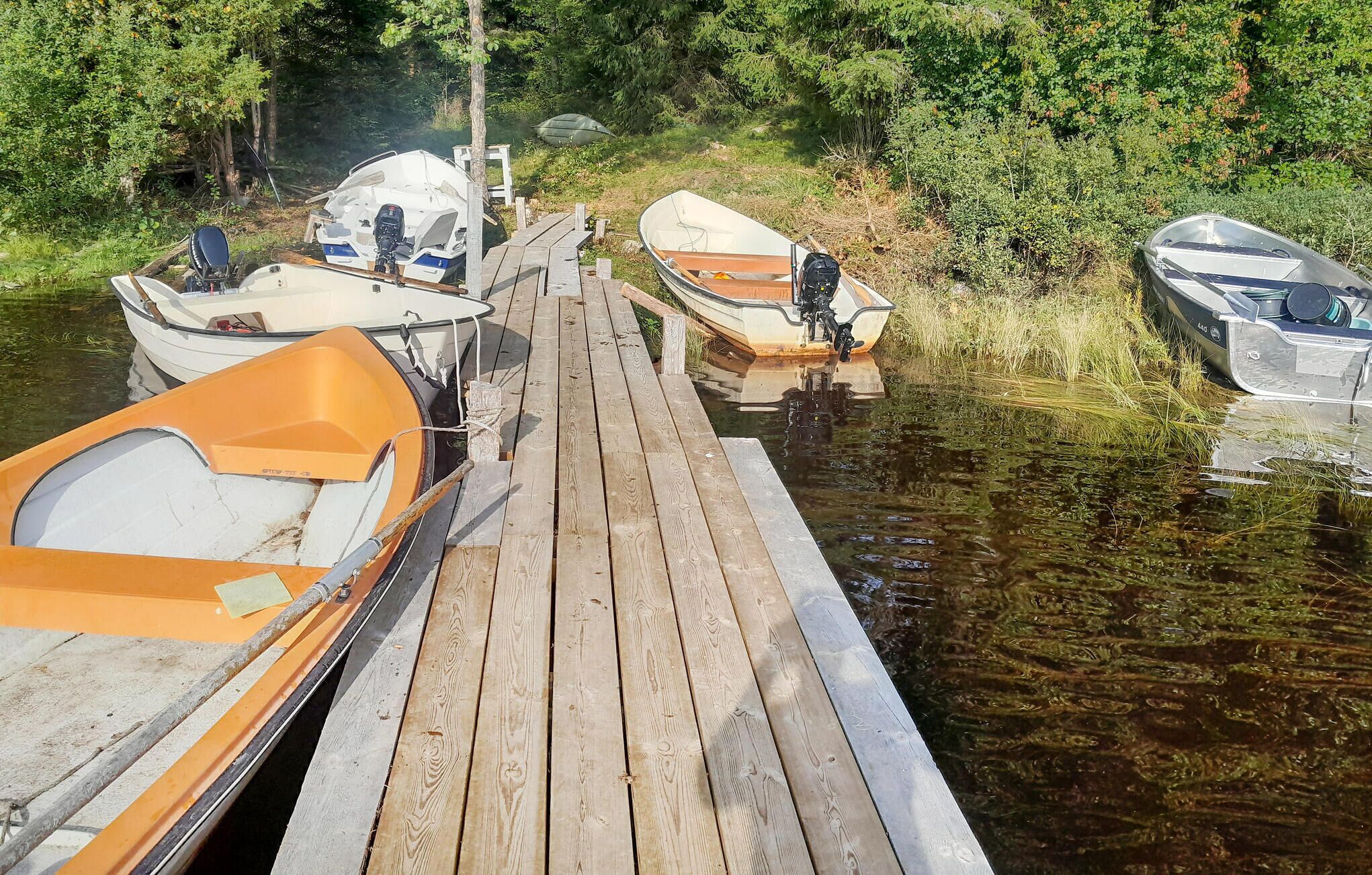 A wooden dock with several boats moored at the end.