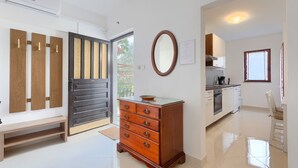 Eine moderne Küche mit weißen Schränken, einem Holzschrank und einem Essbereich mit einem weißen Stuhl.