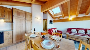 Eine gemütliche Küche mit Holzausbau, einem Esstisch für vier Personen und einem roten Ledersofa im Wohnbereich.
