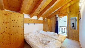 Ein Schlafzimmer in einer Holzhütte mit einem Bett, einem Kleiderschrank und einem Balkon mit einer Kamera auf einem Stativ.