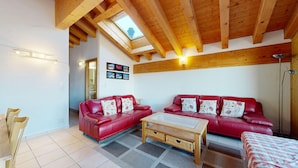 Ein Wohnzimmer mit zwei roten Ledersofas, einem Holztisch und einem Oberlicht.