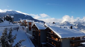 A snow-covered mountain resort with wooden buildings, a ski lift, and a clear view of the mountains. - Mélèzes R 020 - SKI LIFT apartment 8 people (Veysonnaz)