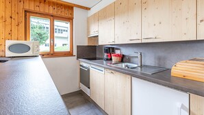 A modern kitchen with wooden cabinets, a microwave, a coffee maker, and a sink. - Mélèzes R 020 - SKI LIFT apartment 8 people (Veysonnaz)