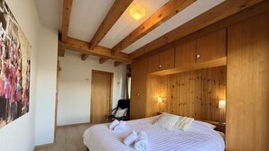 Une chambre à coucher avec un grand lit, des murs recouverts de panneaux de bois, une chaise et un tableau accroché au mur.