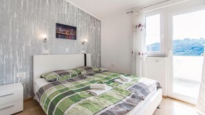Een slaapkamer met een bed, een stadsgezicht aan de muur en uitzicht op een heuvel door het raam.
