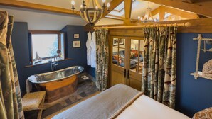 A bathroom with a freestanding bathtub, a window, and a wooden ceiling structure. - Luxury, romantic boathouse on the shores of Lake Ullswater, perfect for special occasions. (Ullswater)