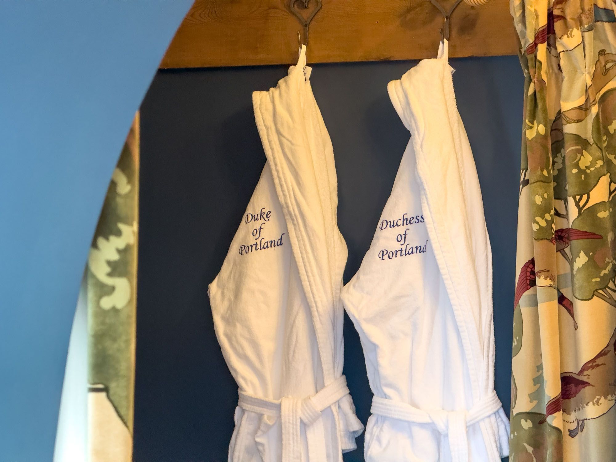 Two white robes hanging on hooks with "Duke of Portland" embroidered on them.