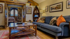 A cozy living room with a blue sofa, wooden coffee table, and a large window with a view of the countryside. - Luxury, romantic boathouse on the shores of Lake Ullswater, perfect for special occasions. (Ullswater)