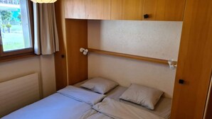 A small, single-bed room with a wooden headboard and a window with curtains. - Greppons P 003 - MOUNTAIN apartment 7 pers (Veysonnaz)