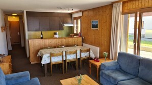 A cozy room with a dining table, chairs, a sofa, and a small table with a vase. - Greppons P 003 - MOUNTAIN apartment 7 pers (Veysonnaz)