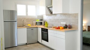 Une cuisine moderne avec des meubles blancs, un réfrigérateur en acier inoxydable, un lave-vaisselle, un four à micro-ondes et un four traditionnel.