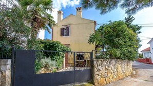 Uma casa de dois andares com uma parede de pedra e um portão de metal na frente.