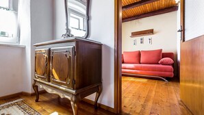 Quarto com armário de madeira, sofá vermelho e teto de madeira.