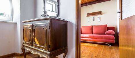 A room with a wooden cabinet, a red sofa, and a wooden ceiling.