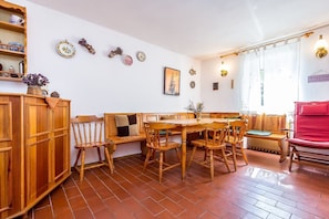 A dining area with wooden furniture, a tiled floor, and wall decorations including plates and a framed picture.