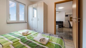 Een slaapkamer met een bed, twee handdoeken, een kledingkast, een deur naar een kitchenette en een raam.